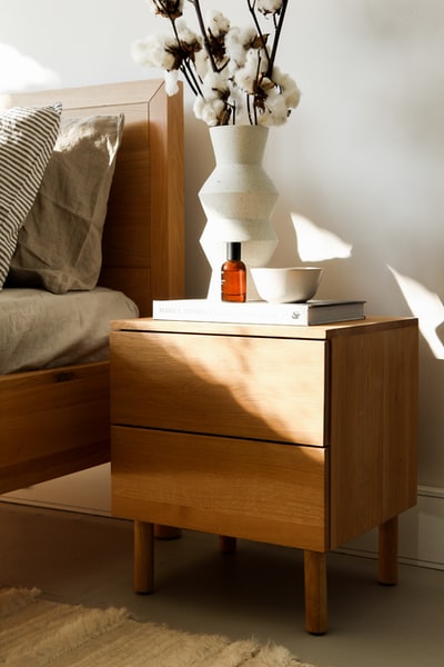 棕色木制床头柜上的白色陶瓷花瓶